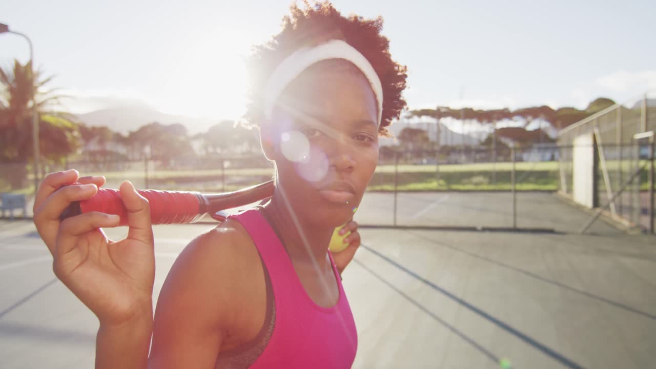 Video of african american female tennis player holding racket and looking at camera