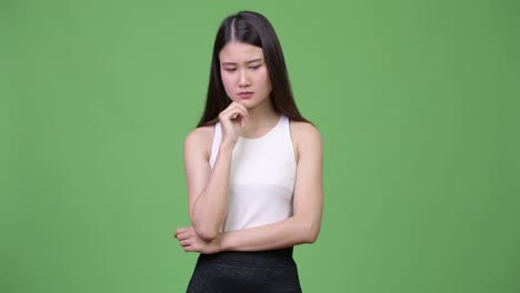 젊은 아름다운 아시아 사업가 여성이 생각하고 있습니다.