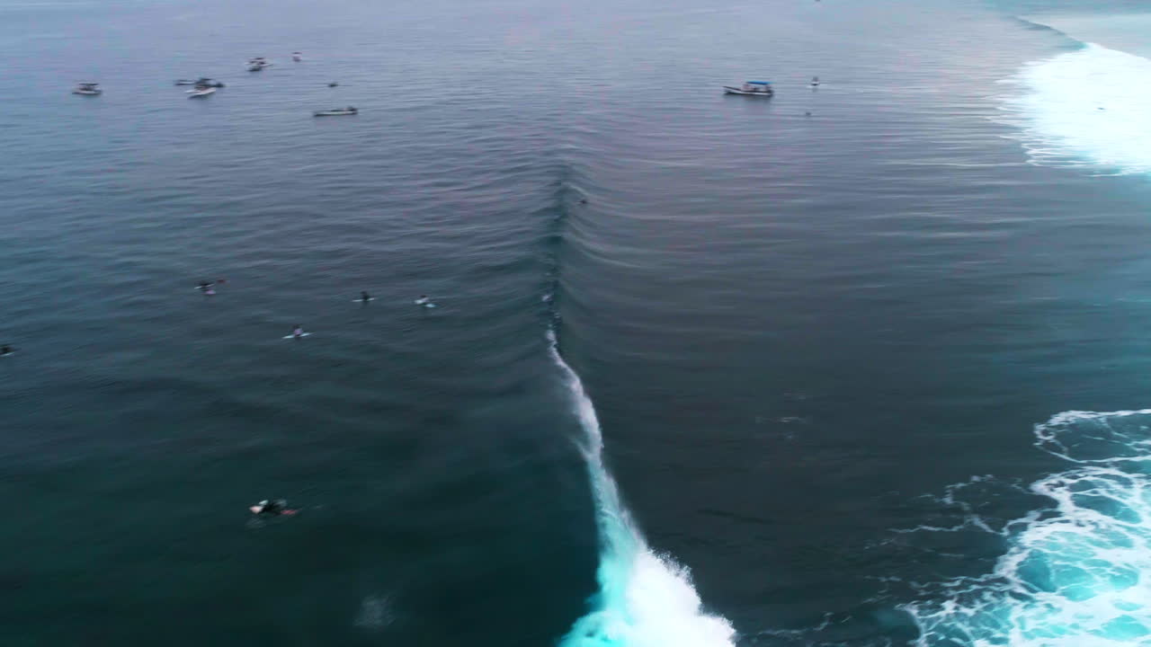 Drone overview of crashing wall of wave water at Cloudbreak Fiji above surfers