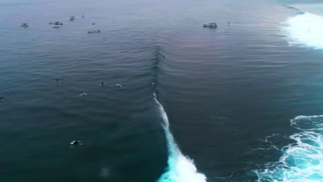 drone overview of crashing wall of wave water at cloudbreak fiji above surfers