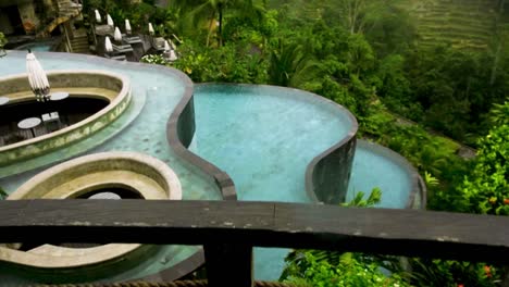 handheld dolly up on rainy luxury pools looking towards terraced forest