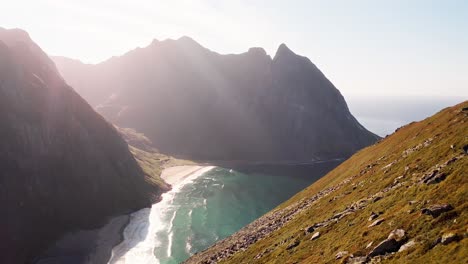 Toma-Aérea-Que-Revela-La-Playa-De-Kvalvika-Mientras-Una-Pareja-Feliz-Y-Su-Perro-Admiran-La-Vista,-Islas-Lofoten,-Noruega