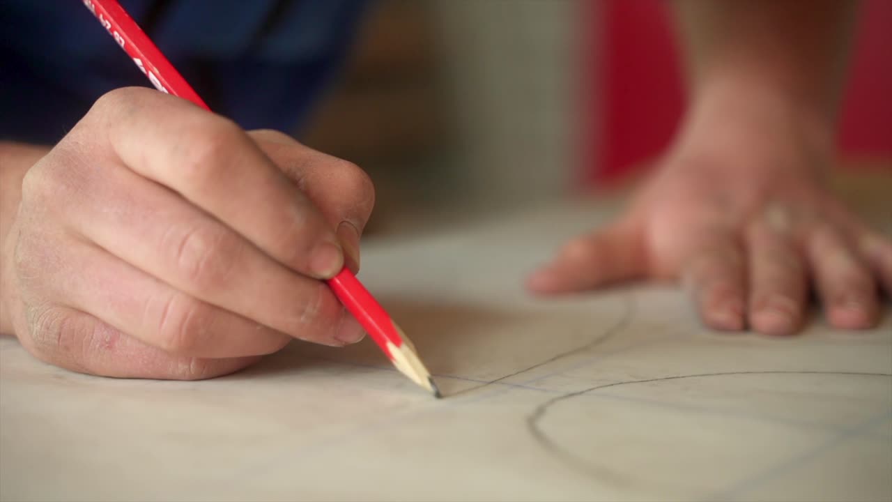 artesano trabajando en un proyecto artístico usando lápices rojos y papel
