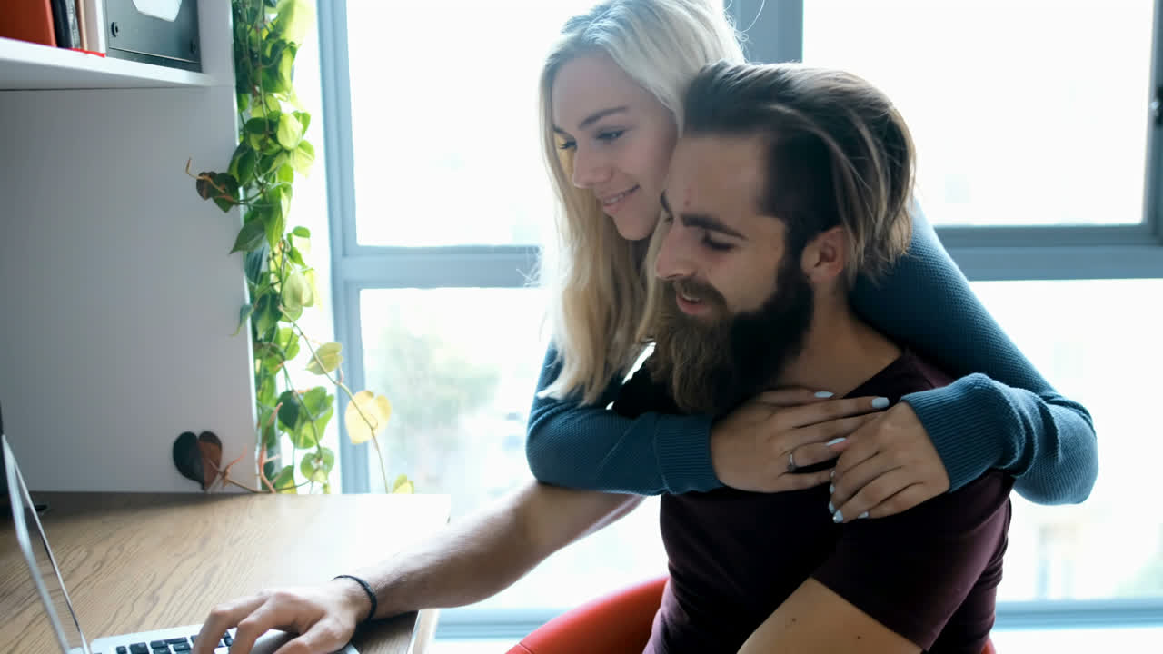 hombre usando computadora portátil mientras la mujer lo abraza desde detrás de 4k