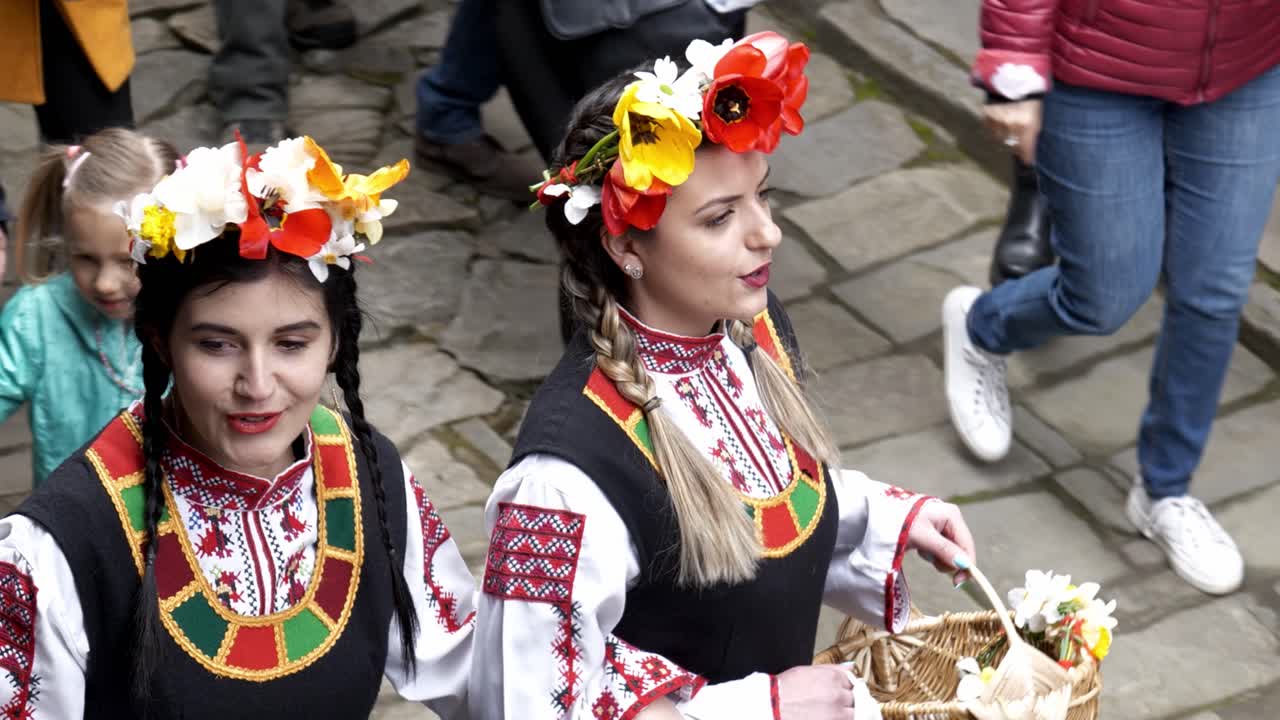 Happy procession of smiling Bulgarian girls in traditional dress in slow motion
