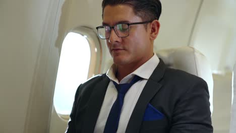 young businessman using laptop computer in airplane