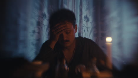 man pondering by candlelight in a dimly lit room