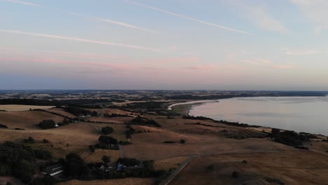 Aerial-view-of-the-coastline-of-Sejerøbugten-with-hills,-fields-and-ocean