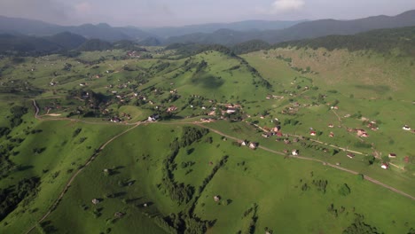 el pueblo de sirnea en rumania con exuberantes colinas verdes y casas esparcidas, día soleado, vista aérea