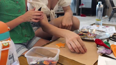 mom and daughter decorating halloween cookies