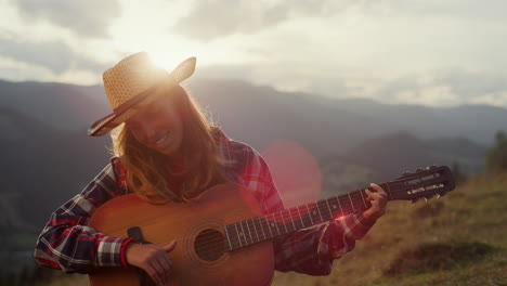 smiling music player perform song on guitar close up. woman play in mountains.