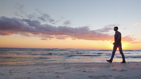 Junger-Einsamer-Mann,-Der-Bei-Sonnenuntergang-Am-Meer-Entlang-Geht