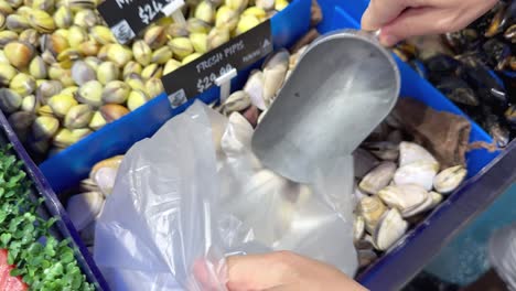 customer scooping clams into a plastic bag