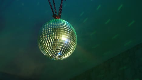 person rotates beautiful rotating sparkling mirror disco ball weighs on the ceiling in the room in the smoke. concept of night retro party