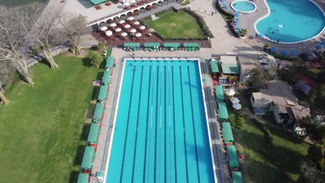 drone video of an olympic sized swimming pool surrounded by green grass and trees