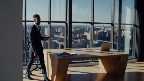 businessman walking through a modern office, engaging with a smartphone while enjoying a panoramic view of the city through a large window, exuding confidence and professionalism