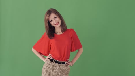 Stylish woman with arms akimbo over green screen