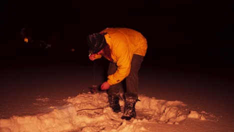 european man ice fishing on a winter night