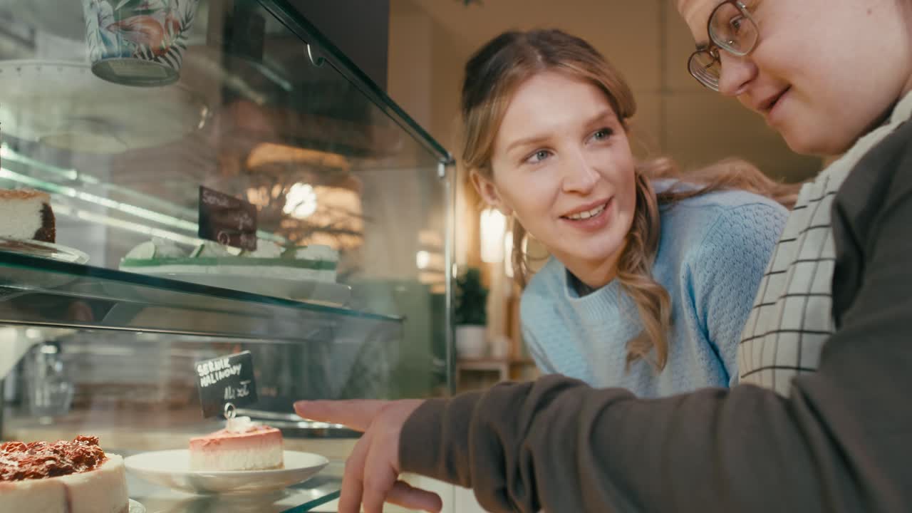 Primo piano di una ragazza con sindrome di Down che consiglia un cliente su quale torta scegliere.