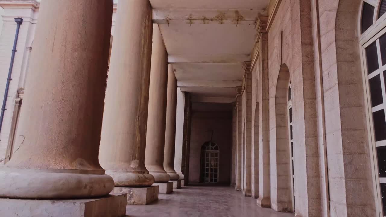 Low angle dolly in of an imposing hallway with old columns at Mapo Hall in Ibadan, Nigeria