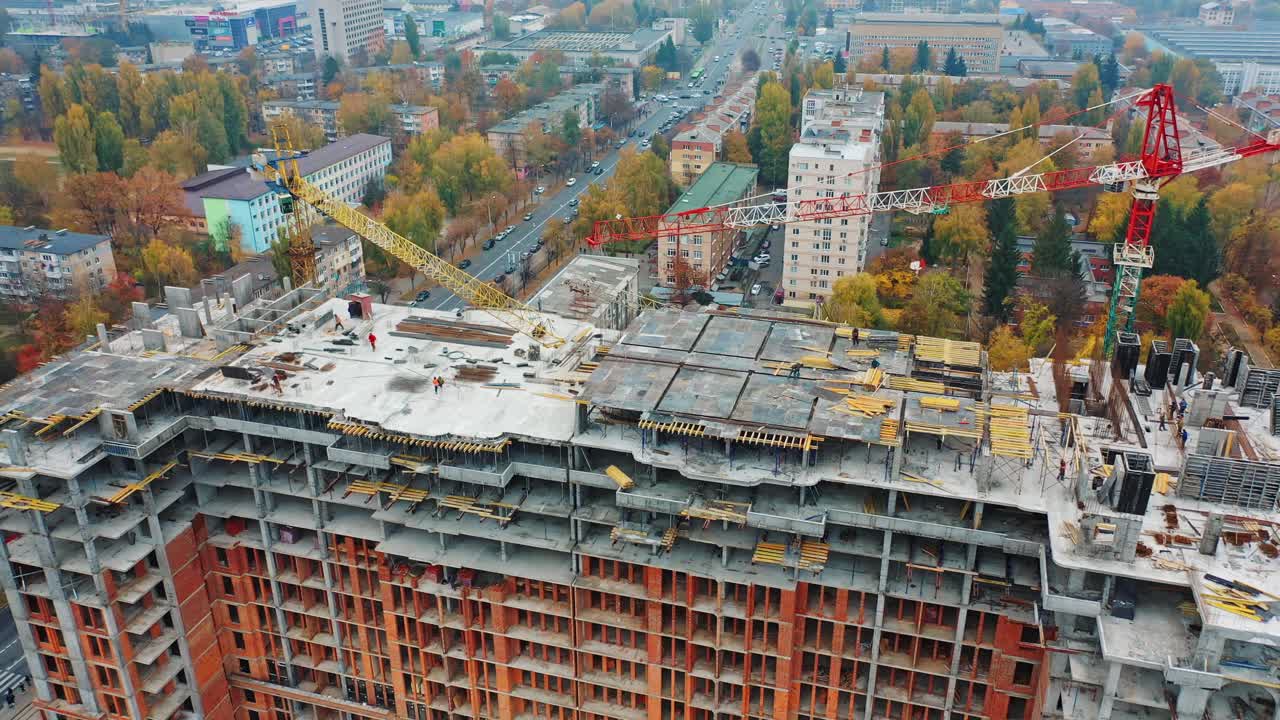 Labor working at construction site. Aerial shot of the building in the process of construction