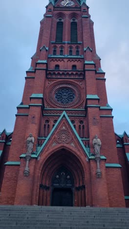 vertical shot of the ornate entrance of st. john’s church in central stockholm, sweden, framed by dramatic evening clouds, showcasing its gothic revival details and architectural grandeur