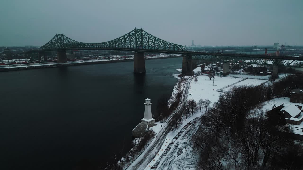 fotografía aérea sobre el parque jean drapeau en la ciudad de montreal con el puente jacques cartier en el fondo y un faro en primer plano en invierno, región de quebec, canadá