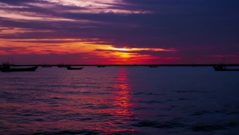 sunset over the ocean with fishing boats