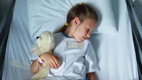 sick girl resting with teddy bear on bed