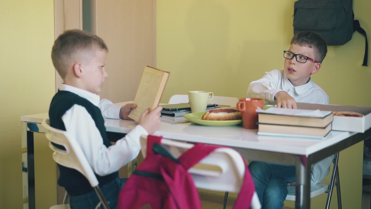 amigos sentados en la mesa con bocadillos frescos y libros de texto en la habitación
