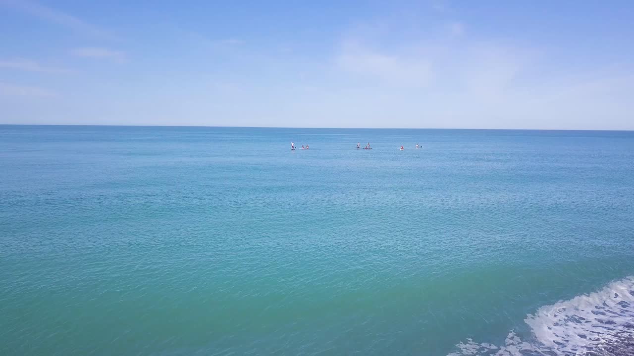 사람들이 조용한 바다에서 패들보딩을 하고 있습니다.