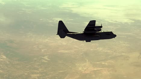 Lockheed-C-130-Hercules-military-transport-aircraft-flying-from-left-to-right-over-a-desert-landscape