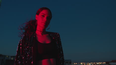 portrait beautiful woman posing with arms crossed at night looking confident with red light in city