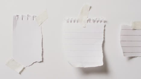 video of close up of three scraps of paper with copy space taped on white background