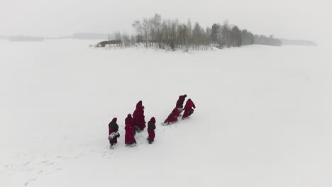 grupo en túnicas rojas en un paisaje nevado