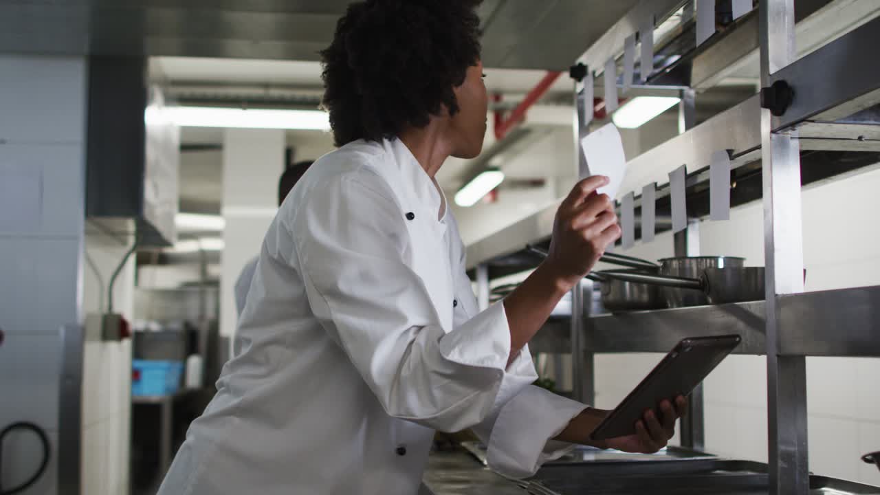 African american female chef taking orders in restaurant kitchen