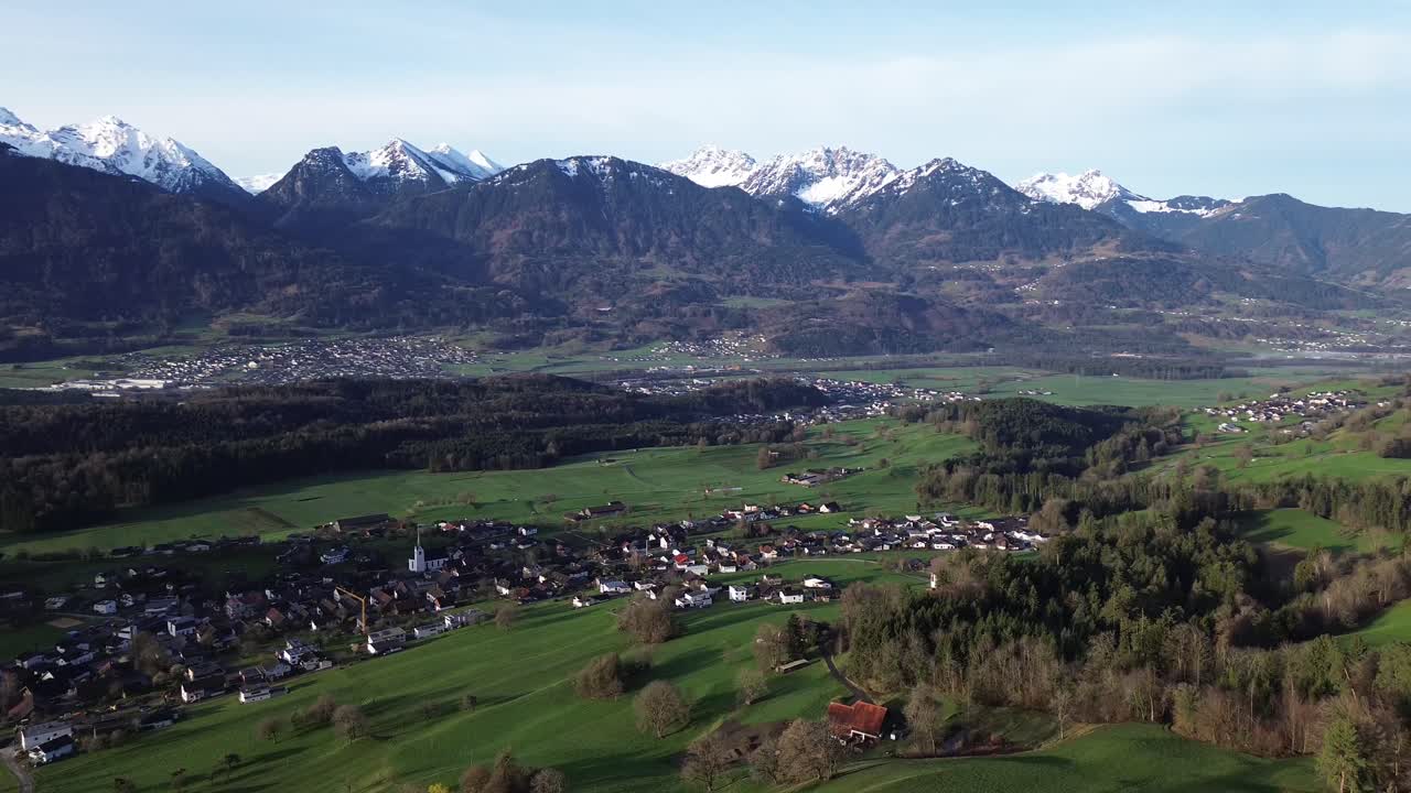 Drone fly above Town in the Mountains with Snow Covered Summits in Background.Vorarlberg, Austria