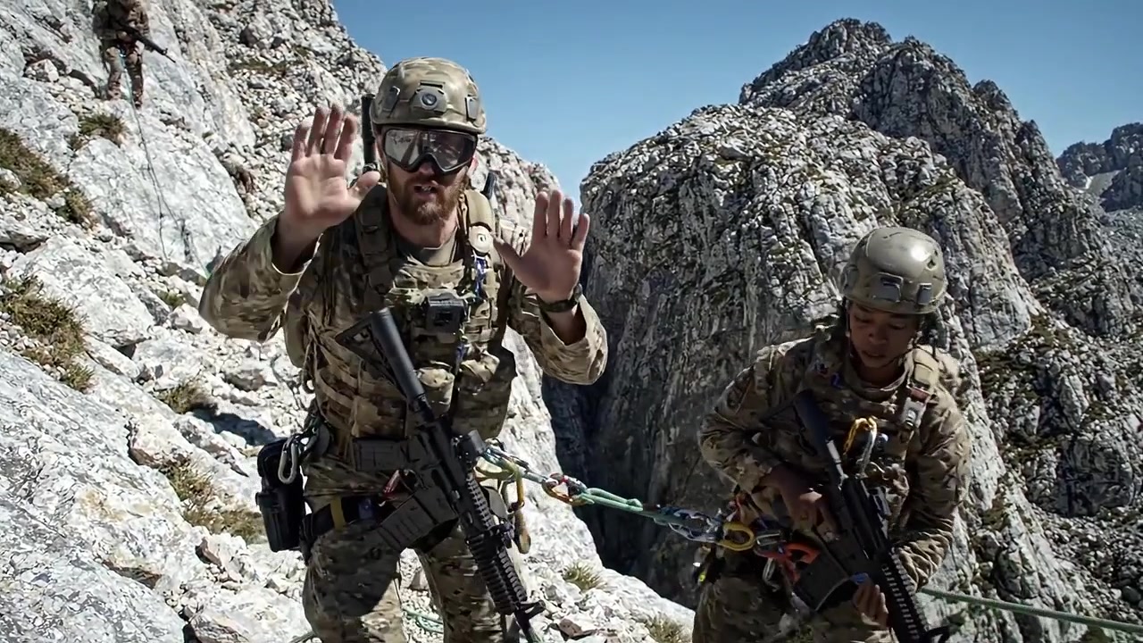 Personale militare che conduce esercitazioni di discesa in corda doppia su terreno montuoso accidentato con scogliere a picco e condizioni difficili in un'esercitazione.
