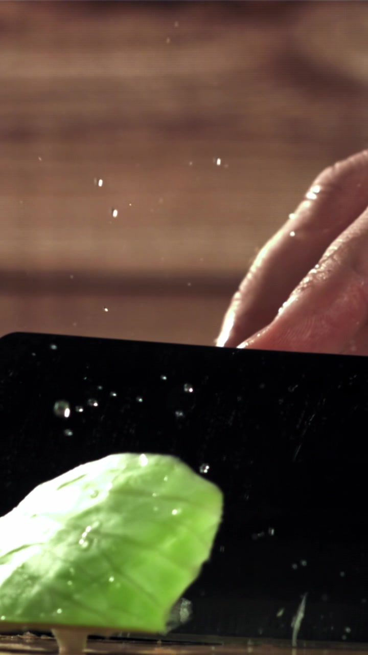 Slow motion close-up of hand cutting fresh lettuce