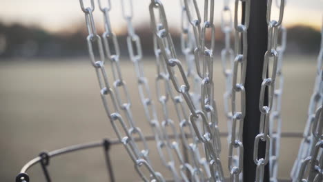 frolf basket chains as disc golfer makes putt with a white frisbee disc