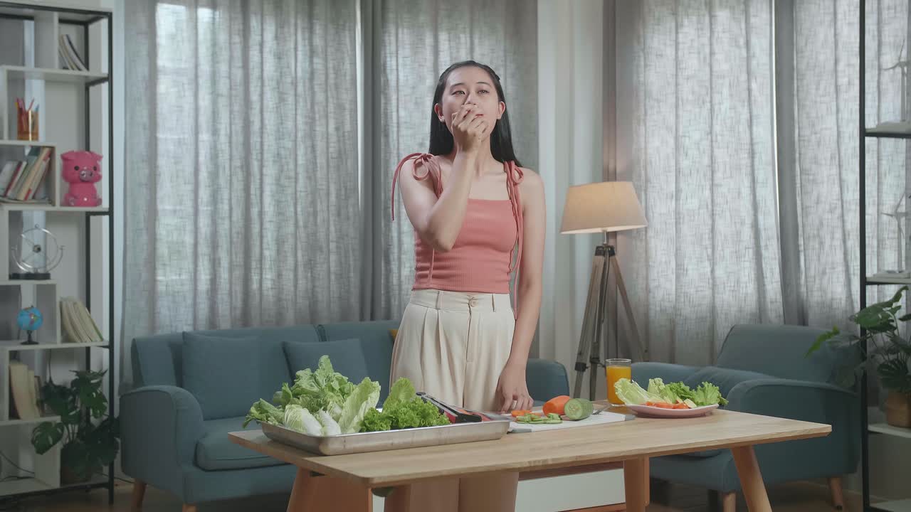 행복 한 아시아 여자 가 집 에서 건강 한 음식 을 먹으면서 사과를 물고 있다