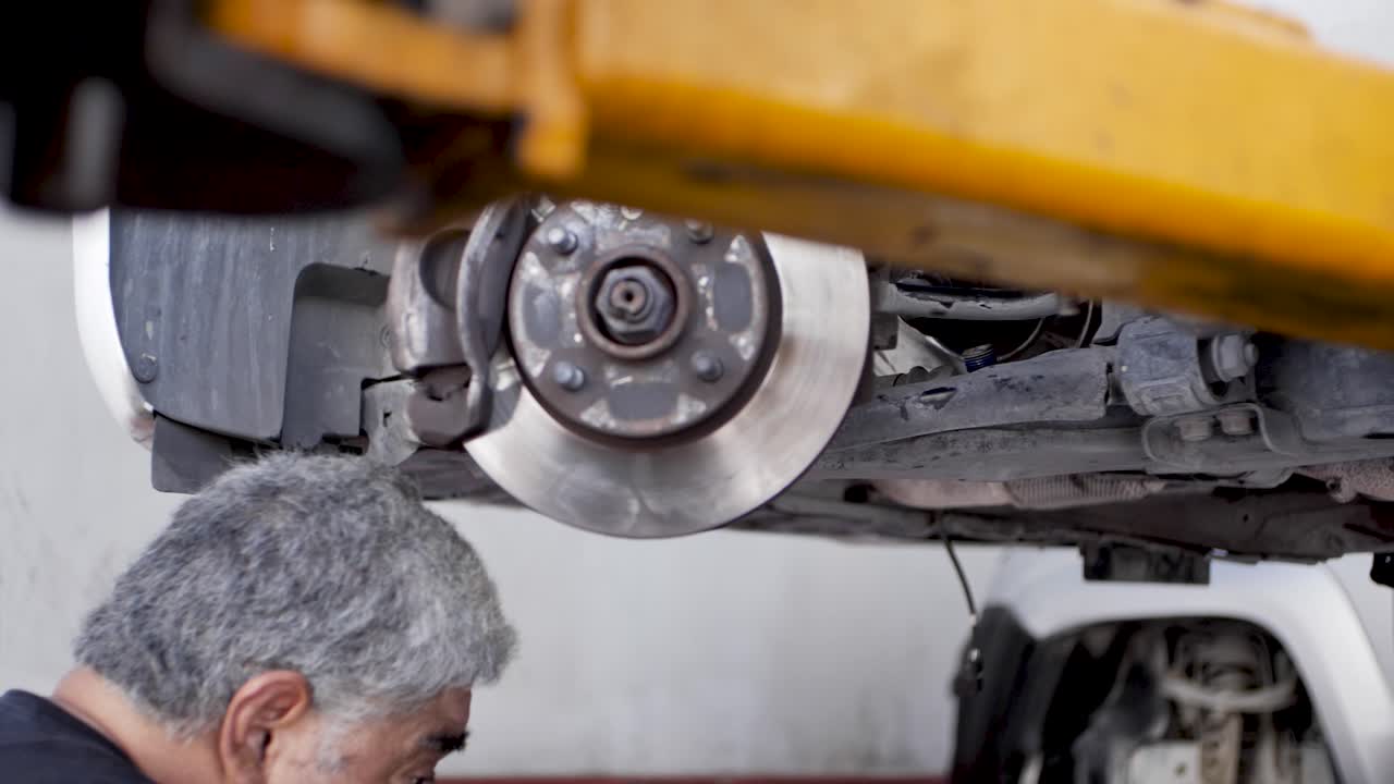 taller de mecánica automotriz inclusivo que permite trabajar a personas mayores en un taller mexicano verificando los discos de freno de un automóvil de un cliente