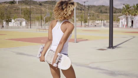 pretty female skater holds board behind her