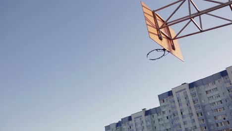 basketball player shooting at a hoop in an outdoor court.