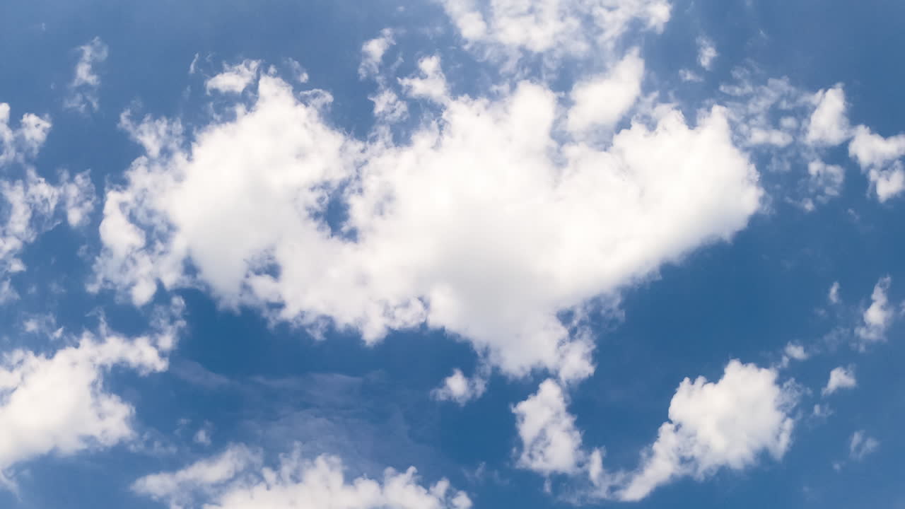 Little soft clouds floating in the sky. Blue skies clearing out. Low angle view. Timelapse.