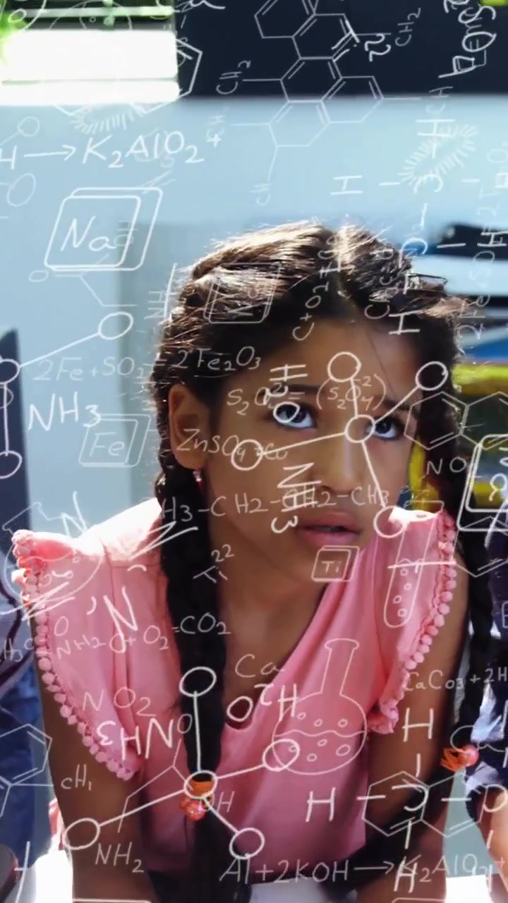 Vertical video: Girl in pink top looking up as adult hand entering, chemistry overlay aiding lesson
