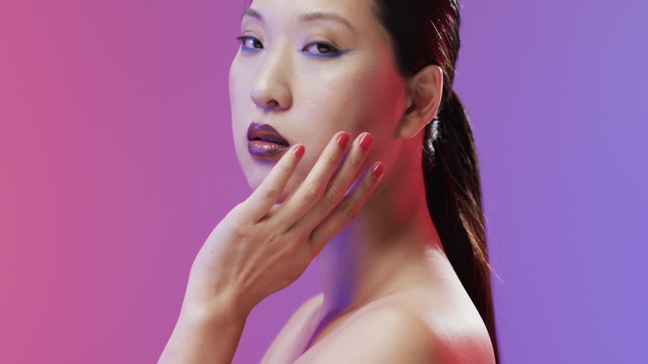 Asian woman with black hair, red lips and make up looking at camera, copy space, slow motion