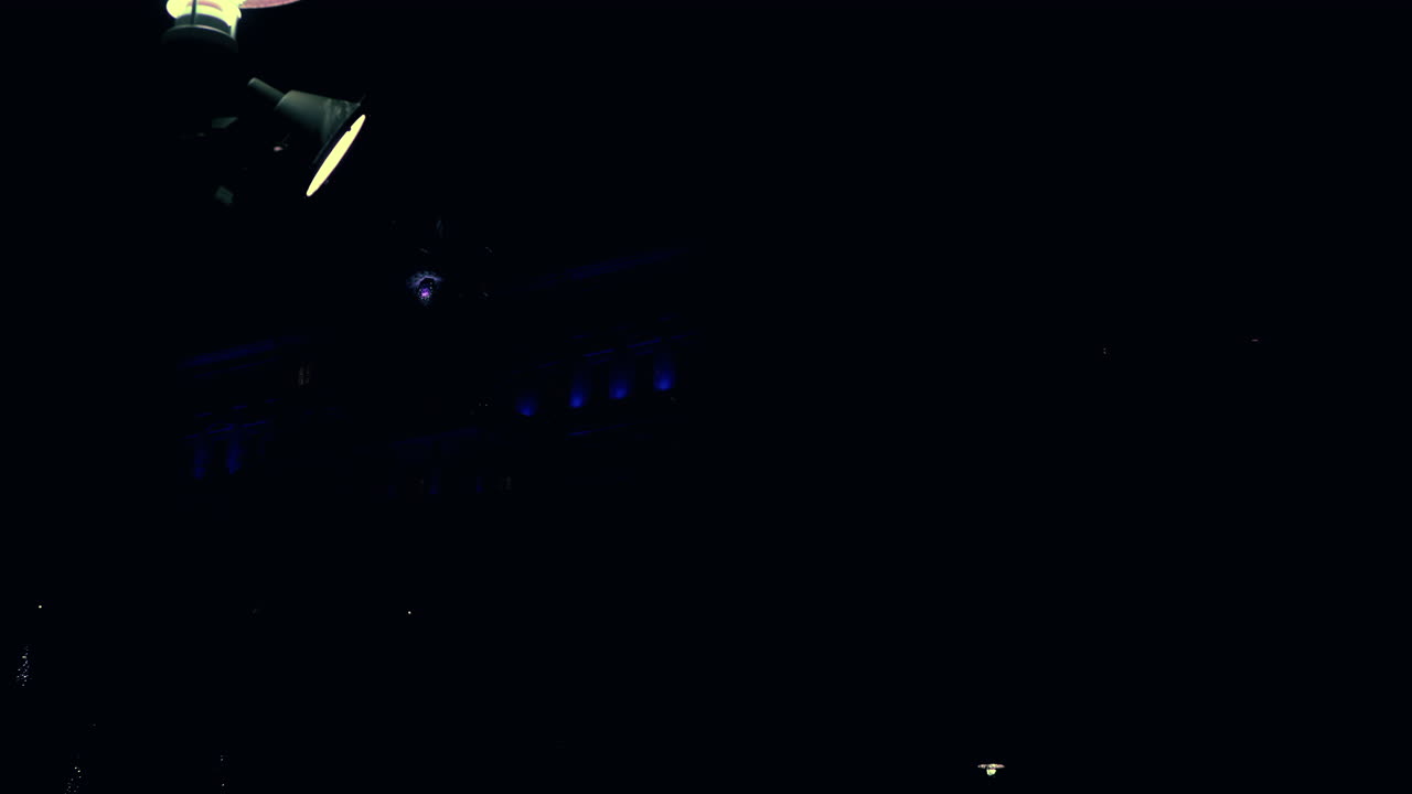 밤에 공원에 있는 가로등의 샷을 확대하고 배경에 조명이 켜진 집이 있습니다.