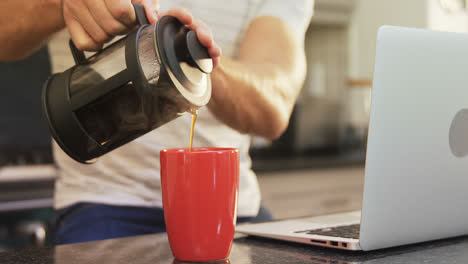 Young-man-pouring-hot-black-coffee-in-mug-4K-4k