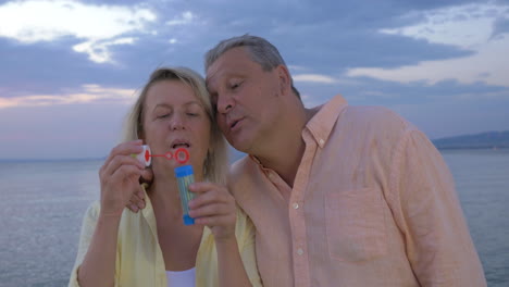 mature couple blowing bubbles on the coast